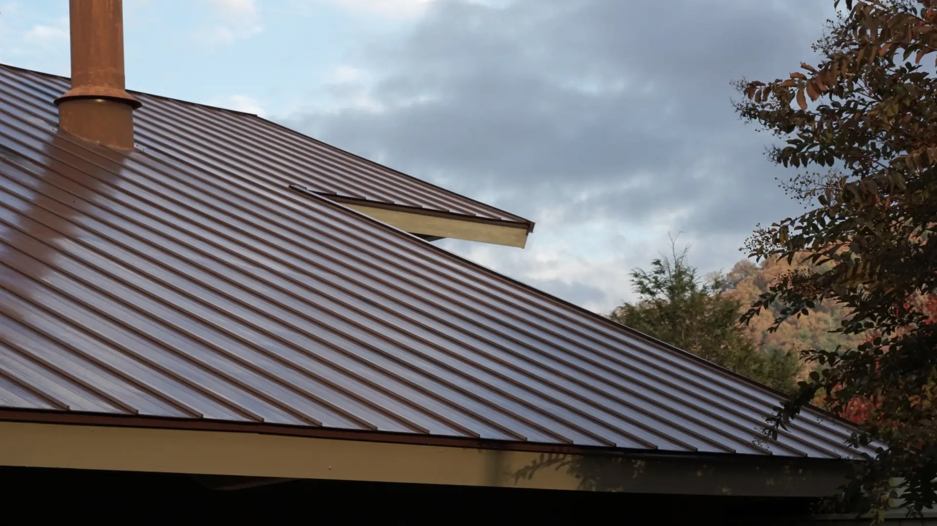 Brown metal roof installation with chimney on Michigan home